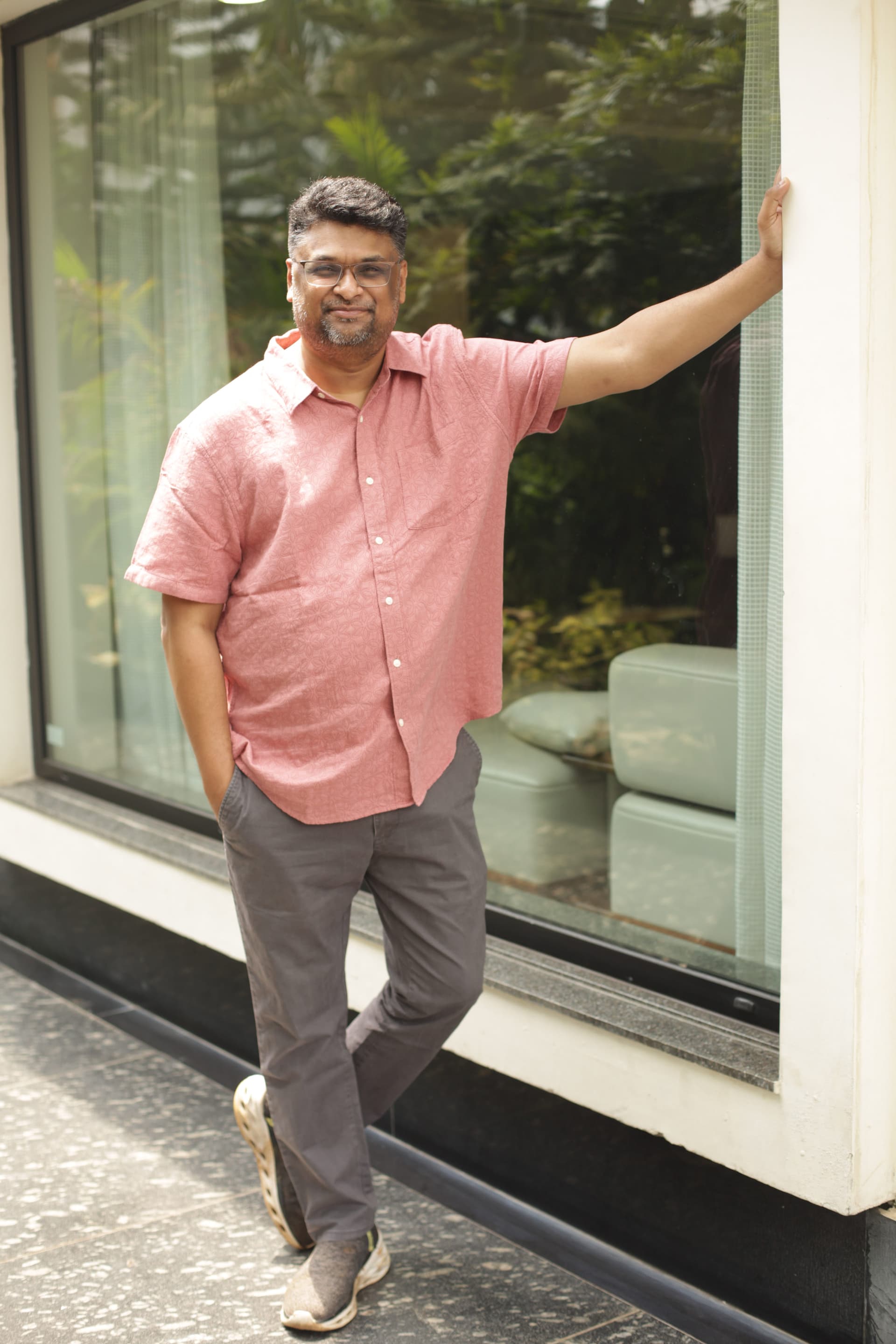Hussain Sha Kiran standing beside a modern window