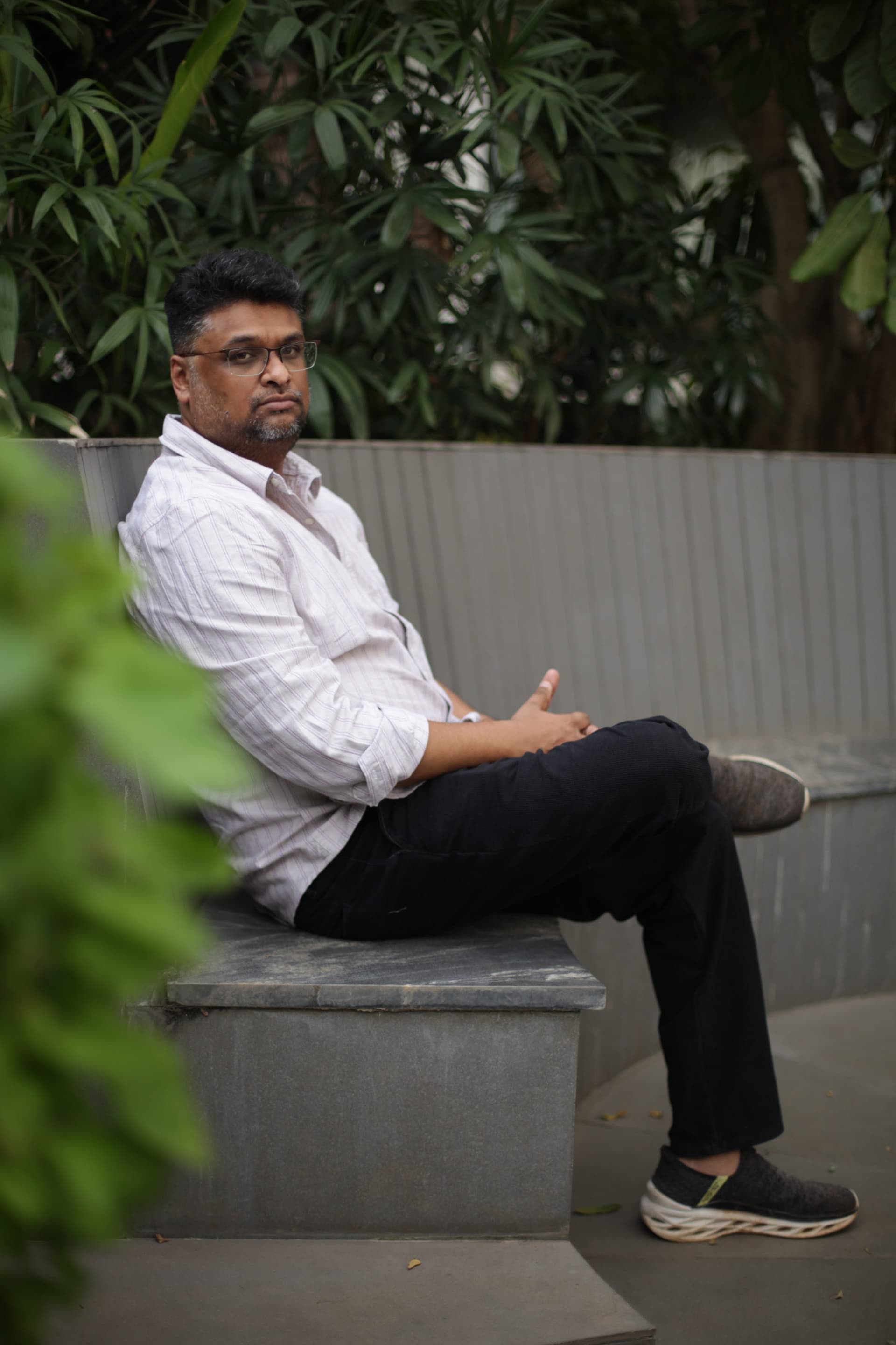 Hussain Sha Kiran seated outdoors in a white shirt